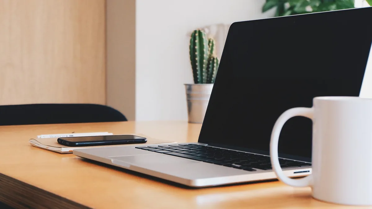 A laptop, notebook and mug on a tidy desk