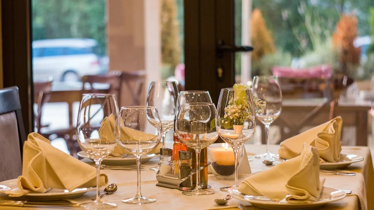 A restaurant table laid with glassware, napkins and candlelight